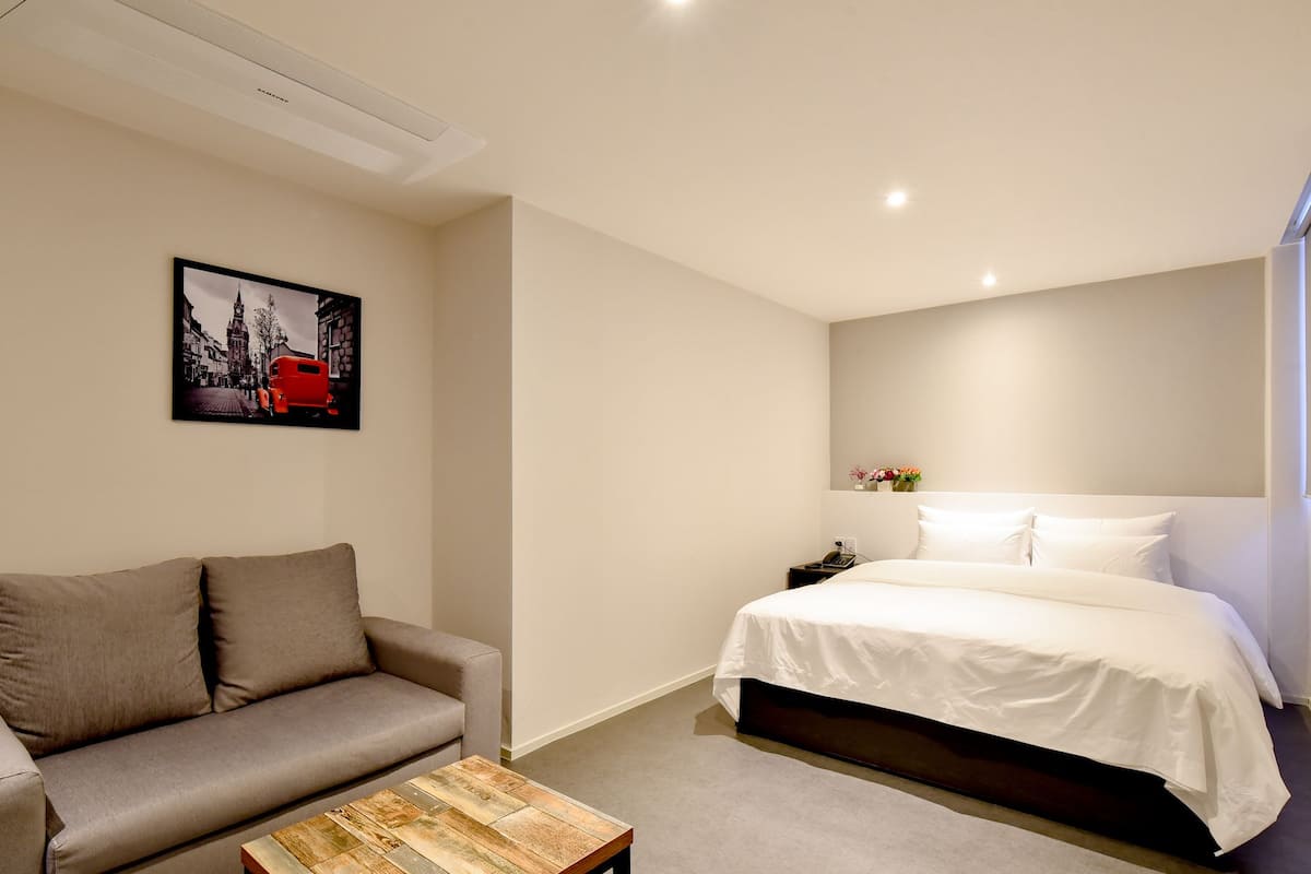 Ein modernes Hotelzimmer mit einem Bett, einer Couch, einem Couchtisch und einem Wandbild.