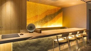 A modern conference room with a long table, six chairs, and a large wall-mounted screen.