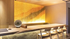 A modern dining area with a long wooden table, six chairs, and a decorative wall with a textured pattern.