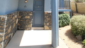 A two-story building with a stone foundation, a blue exterior, and a balcony on the upper floor.