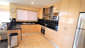 A modern kitchen with black countertops, beige cabinets, a stainless steel refrigerator, and a microwave.