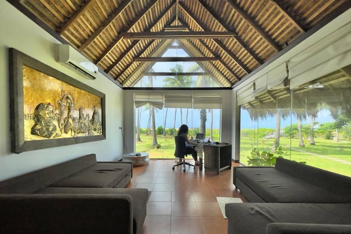 A room with a high ceiling, a large window, and a view of the outdoors.