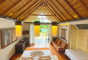 Um quarto amplo com teto de madeira alto, um sofá, uma cama e um espaço para refeições.