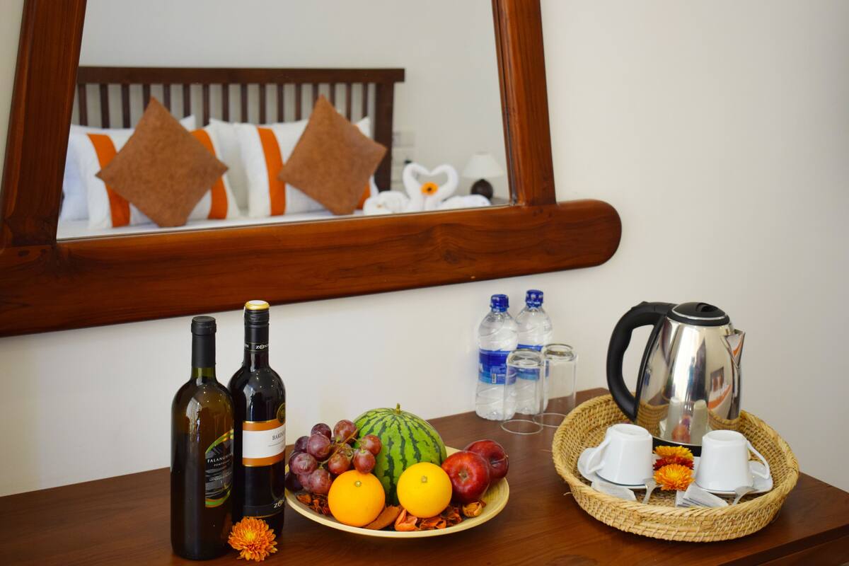 A breakfast setup with wine bottles, fruits, and a coffee pot on a wooden table.