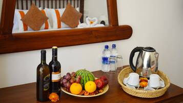 A breakfast setup with wine bottles, fruits, and a coffee pot on a wooden table.