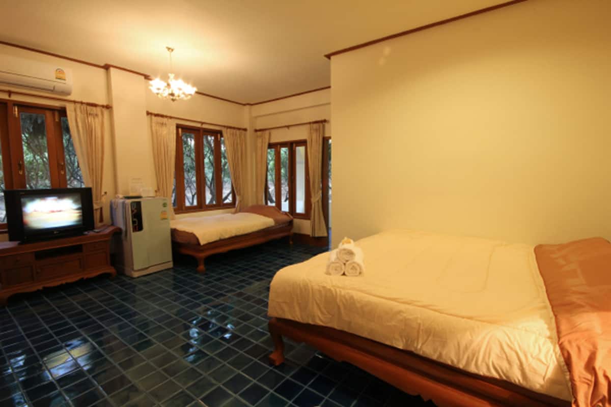 A hotel room with a bed, a television, a refrigerator, and a window with curtains.
