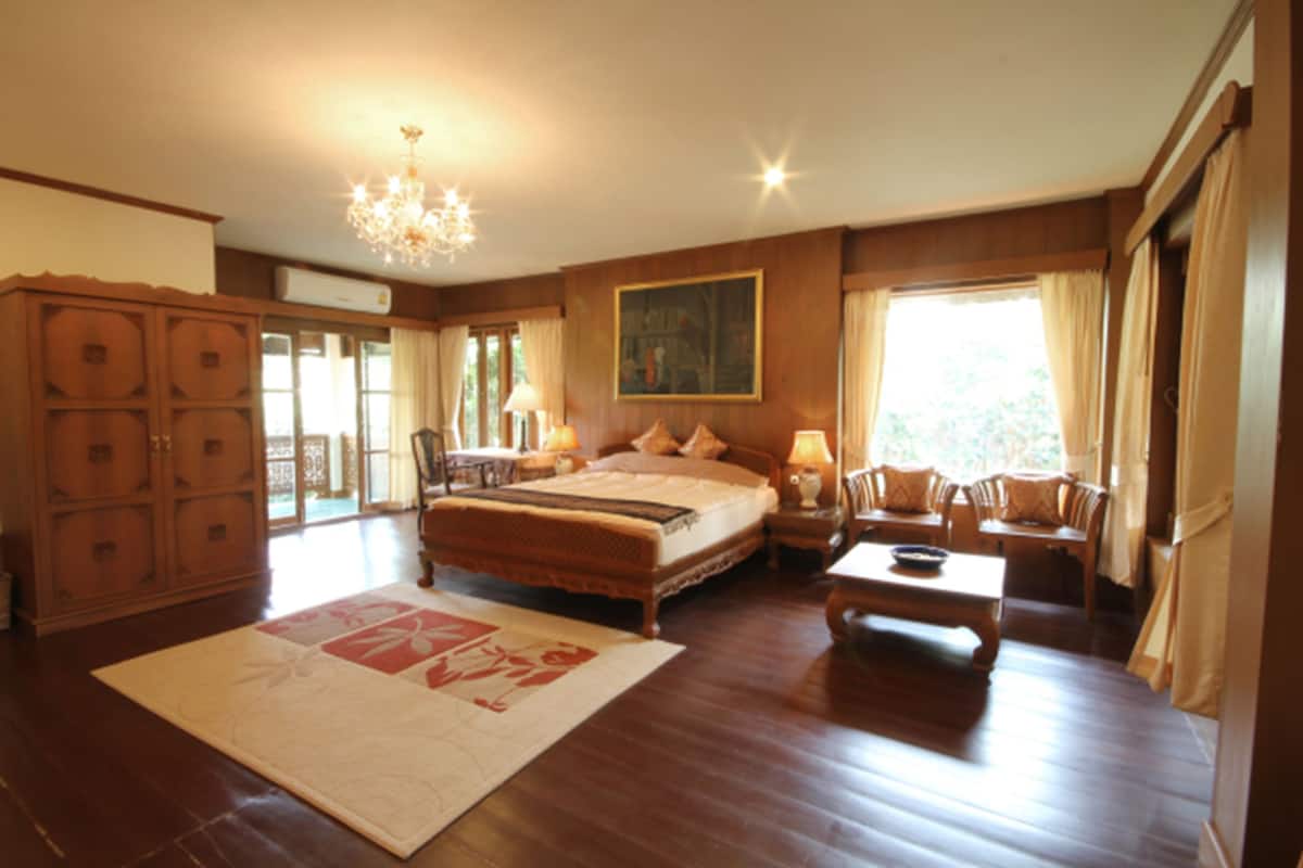 A spacious bedroom with a large bed, a sitting area with a table and chairs, and a chandelier.