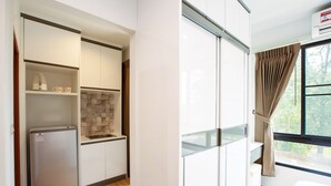 Una cocina compacta con refrigerador integrado, un lavamanos y un ventanal con cortinas.