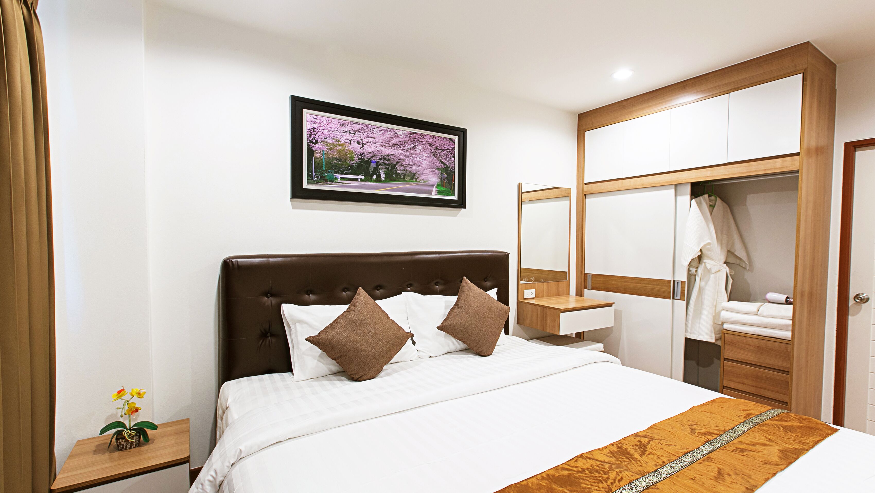 A neatly arranged bedroom with a bed, bedside table, and a large mirror.