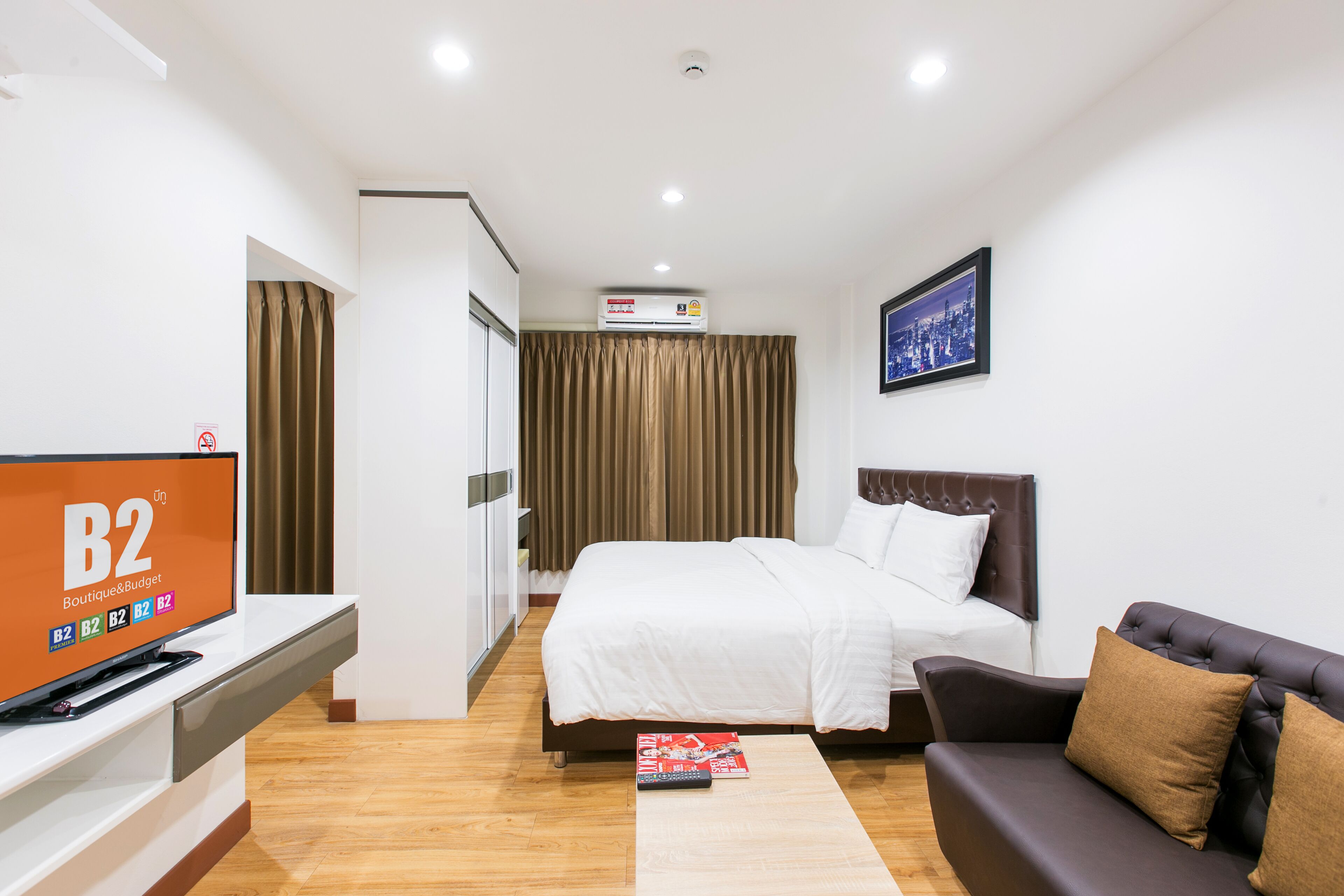 A hotel room with a bed, a TV, a couch, and a framed picture on the wall.