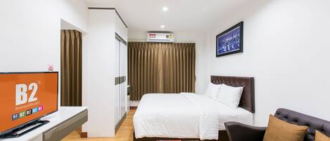 A hotel room with a bed, a TV, a couch, and a framed picture on the wall.