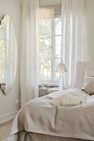 A bedroom with a bed, a lamp, and a window with curtains.