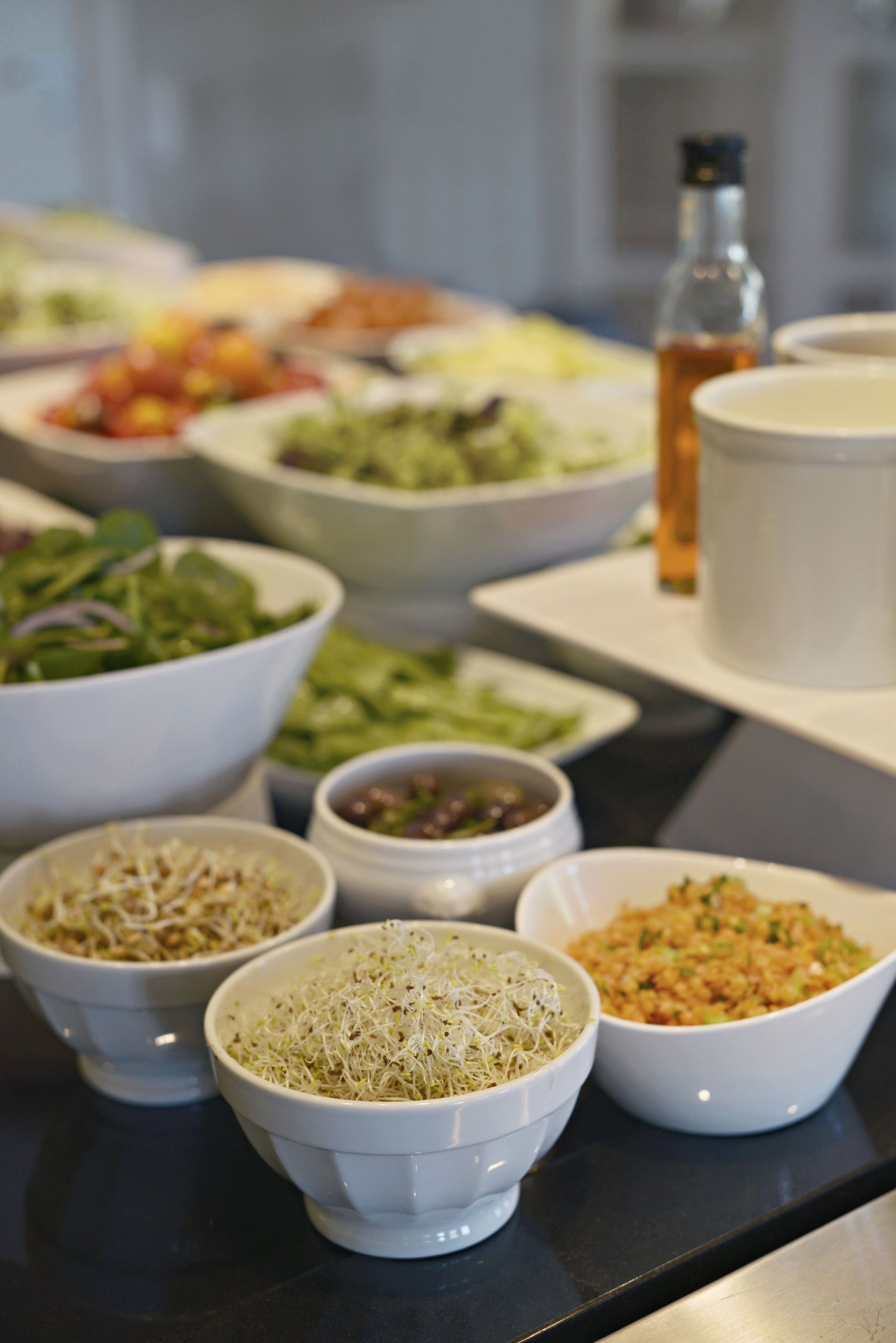 A buffet table with various dishes including salads, sprouts, and other food items.