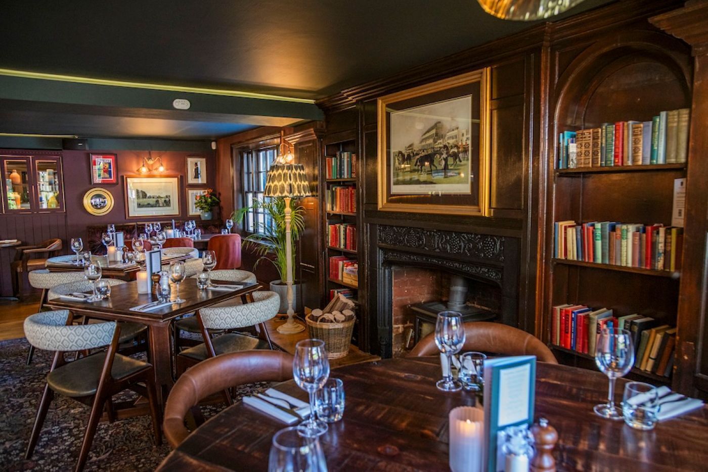 A cozy restaurant with wooden furniture, a fireplace, and bookshelves.
