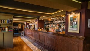 A bar area with a long counter, shelves with bottles, and a tiled floor. - The Royal Foresters, Ascot, Berkshire - Acorn Pubs (Ascot)