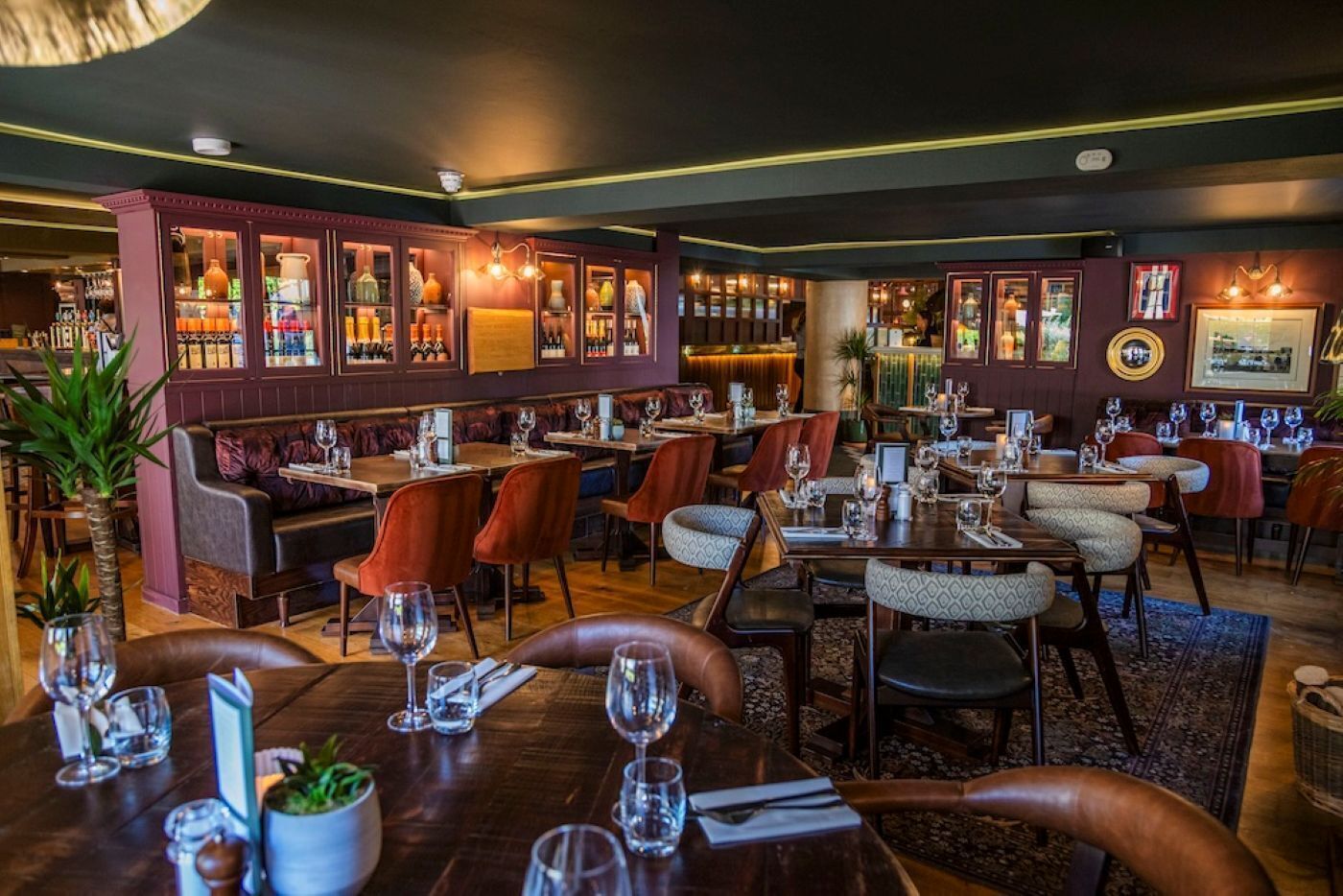 A restaurant with booths and tables, bar area, and various bottles on shelves.