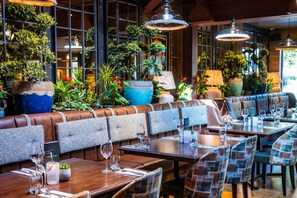 A restaurant interior with booths, tables, and hanging plants. - The Royal Foresters, Ascot, Berkshire - Acorn Pubs (Ascot)