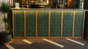 A reception area with a green tiled wall, a wooden frame, and a potted plant. - The Royal Foresters, Ascot, Berkshire - Acorn Pubs (Ascot)