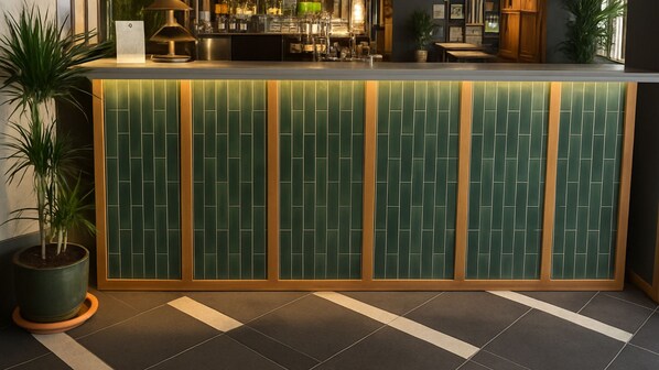 A reception area with a green tiled wall, a wooden frame, and a potted plant. - The Royal Foresters, Ascot, Berkshire - Acorn Pubs (Ascot)