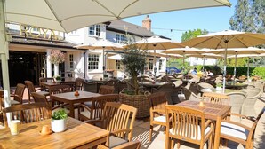 An outdoor seating area with wooden tables and chairs, umbrellas, and a sign that reads 'ROYAL'. - The Royal Foresters, Ascot, Berkshire - Acorn Pubs (Ascot)