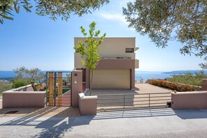 A modern two-story building with a flat roof, a garage door, and a small balcony.