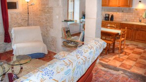 Une pièce confortable comprenant un lit, une chaise, une petite table et un coin cuisine.