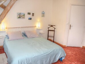 A bedroom with a bed, two bedside tables, a hanging rack, and a door.