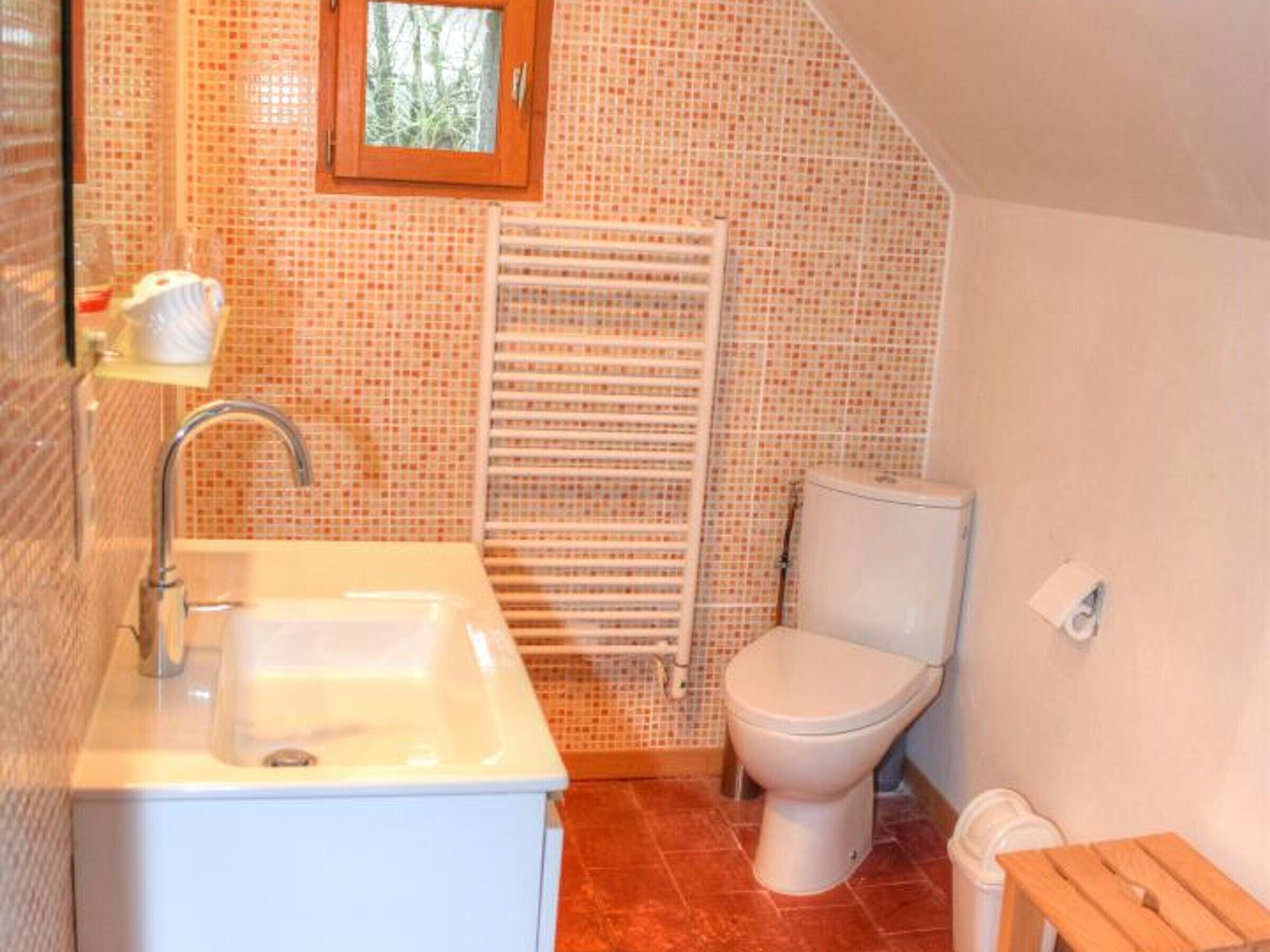 Une salle de bain avec un lavabo, des toilettes et une fenêtre située au-dessus des toilettes.