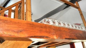 Un lliteroset de fusta amb matalàs estampat, sostre inclinat i bigues al descobert.