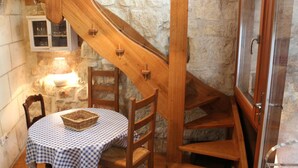 Una escala de fusta amb un mantell a quadres i cadires, una cistella damunt la taula, i una paret de pedra al fons.