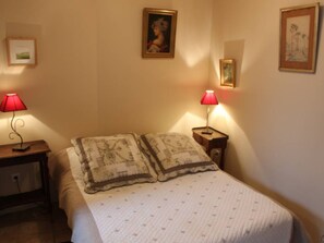 Ein Schlafzimmer mit einem Bett, zwei Nachttischen mit Lampen und drei gerahmten Bildern an den Wänden.