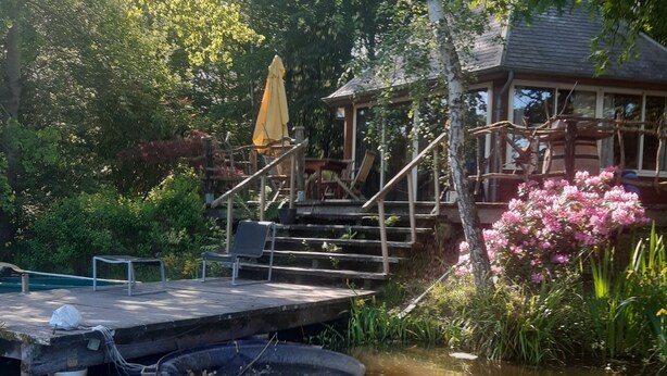 A pond with a wooden dock and steps leading to a gazebo.