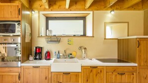 Una cocina compacta con armarios de madera, un microondas, una cafetera y un lavabo.