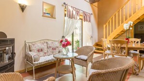Una sala de estar acogedora con un sofá, sillas de mimbre, una mesa de vidrio y una escalera de madera.