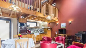 Un interior acogedor con comedor, sillas rojas, televisor y chimenea.