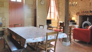 A rustic dining area with a wooden table, chairs, a bench, a fireplace, and a clock on the wall. - Touraine Cottage near Loches with Fireplace and Garden (Saint-Senoch)