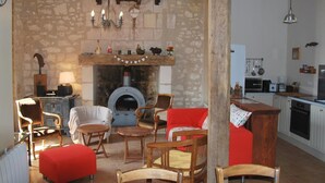 A rustic interior with a stone wall, wooden furniture, a fireplace, and a kitchen area. - Touraine Cottage near Loches with Fireplace and Garden (Saint-Senoch)