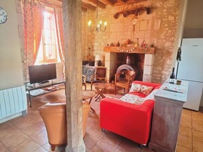 Un salon confortable avec une cheminée, un téléviseur et un coin repas.