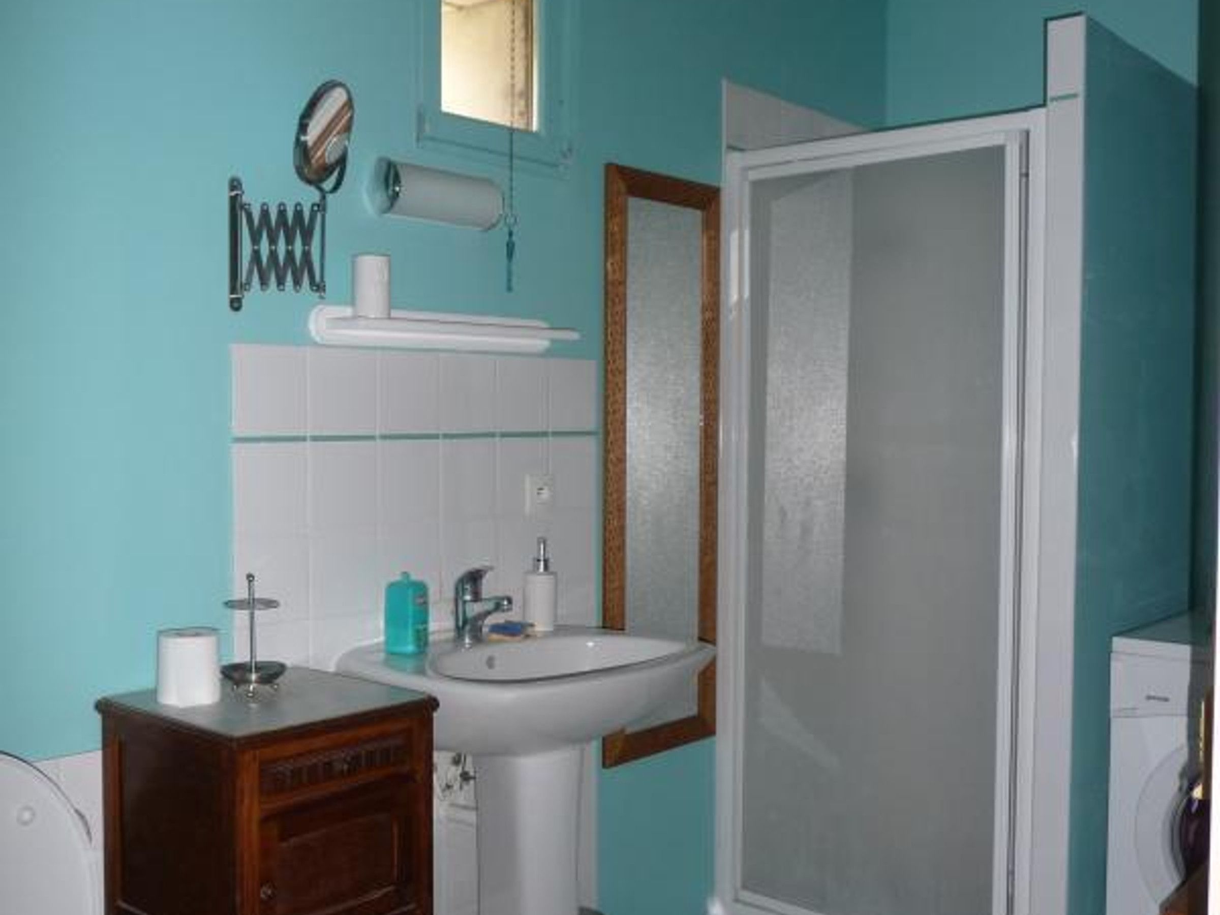 Une salle de bain équipée d’un lavabo, d’un miroir, d’un porte-serviettes et d’un espace douche.