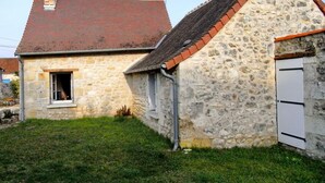 Un bâtiment en pierre avec un toit recouvert de tuiles rouges et une petite fenêtre.