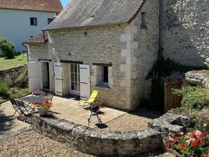 Un bâtiment en pierre doté d’un patio, d’un espace extérieur aménagé pour s’asseoir et d’un petit jardin.