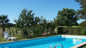 A rectangular swimming pool with a clear blue water surface, surrounded by a grassy area and trees. - Charming 18th Century Cottage with Pool, Near Loire Castles and Vineyards (Saint-Épain)