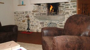 Una sala de estar acogedora con chimenea de piedra, sillones de cuero y un pequeño estante de madera.