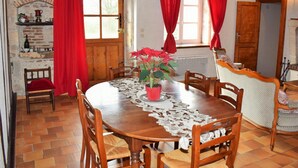 Un coin repas avec une table en bois, des rideaux rouges et une plante en pot.