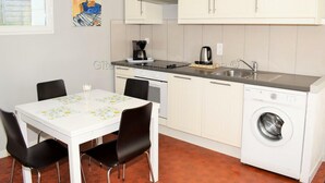 A compact kitchen with a washing machine, a coffee maker, and a dining area with a table and chairs. - Charming house near Loire Valley Castles (Athée-sur-Cher)