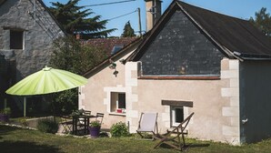 A stone house with a sloped roof, a small balcony, and a green umbrella. - Charming house near Loire Valley Castles (Athée-sur-Cher)