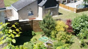 A house with a sloped roof, a visible chimney, and a garden with various plants and a hose. - Charming house near Loire Valley Castles (Athée-sur-Cher)