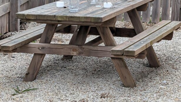 A wooden picnic table with benches, a vase with flowers, and a yellow basket. - Semi-Detached Home in Omonville-la-Rogue with Parking and Pets Allowed (Omonville-la-Rogue)