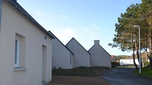 A row of white buildings with a paved driveway and a street lamp. - Semi-Detached Home in Omonville-la-Rogue with Parking and Pets Allowed (Omonville-la-Rogue)