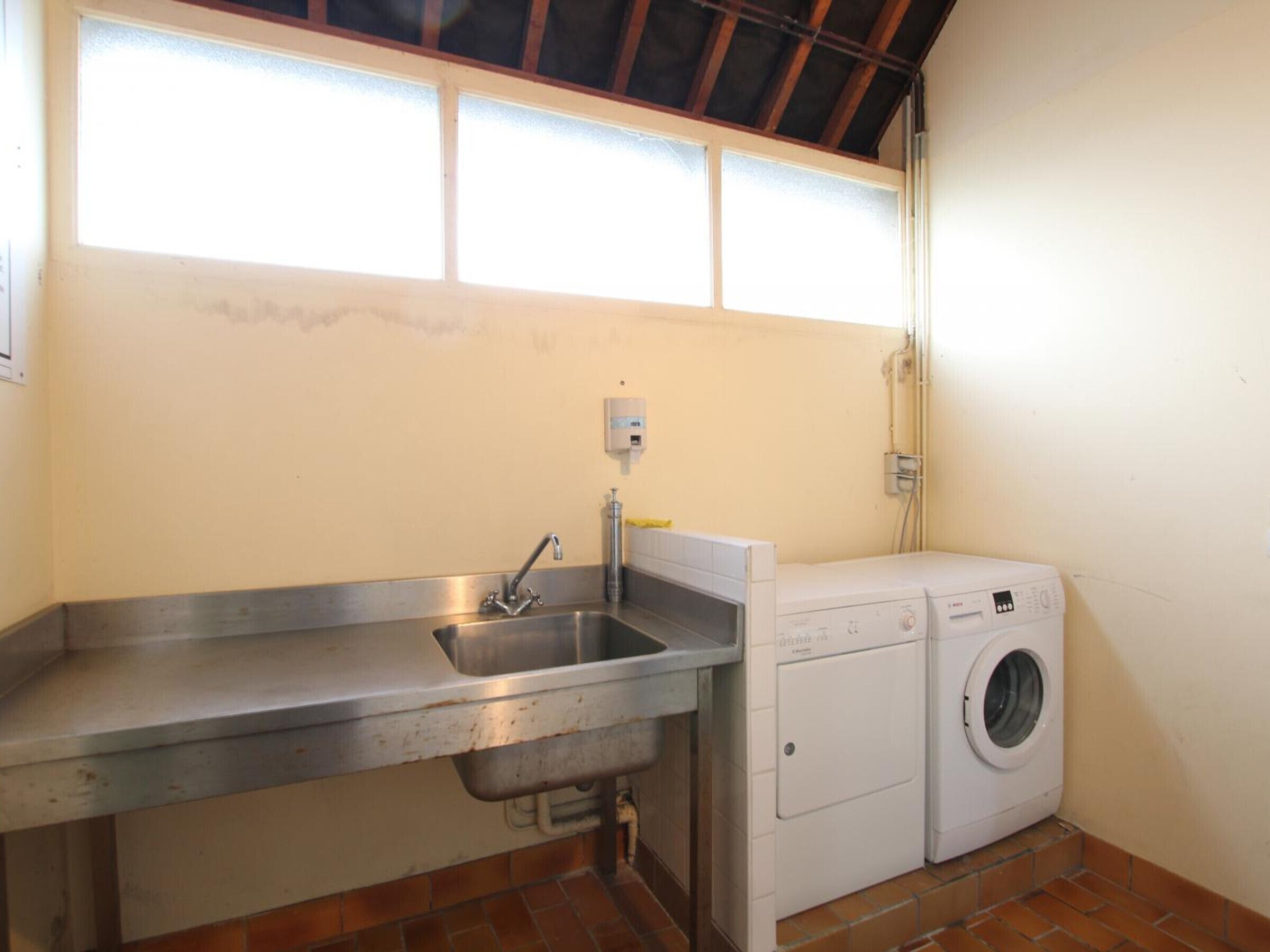 A compact laundry area with a sink, washing machine, and a window above.